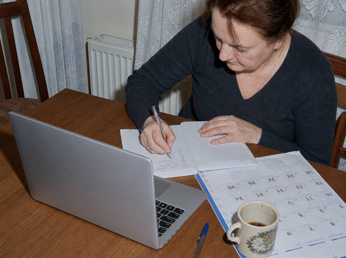 Dokumentowanie faktów: odręczne notatki z datami w zeszycie obok kalendarza i laptopa