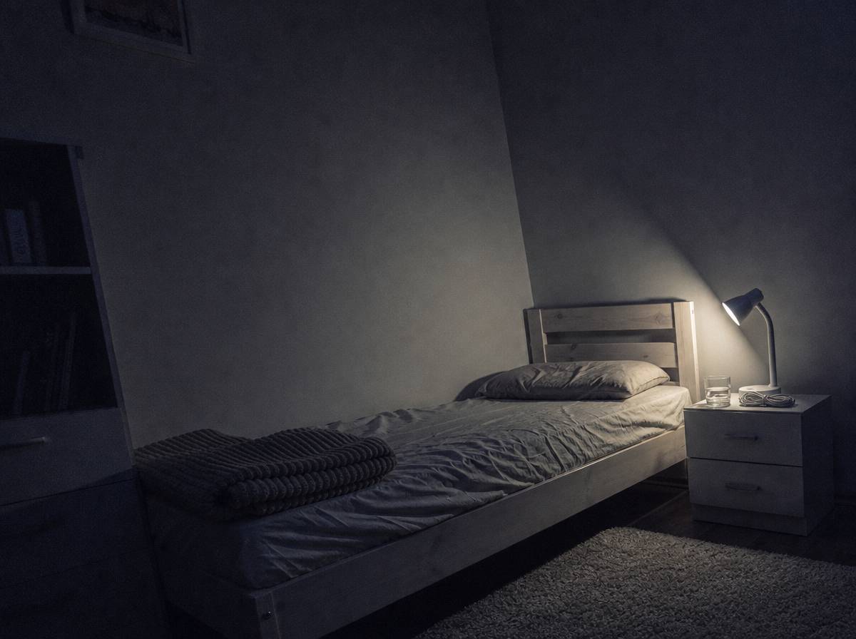 Łóżko dziecka z ciężkim kocem i lampką na szafce – kącik wyciszenia po dniu pełnym bodźców