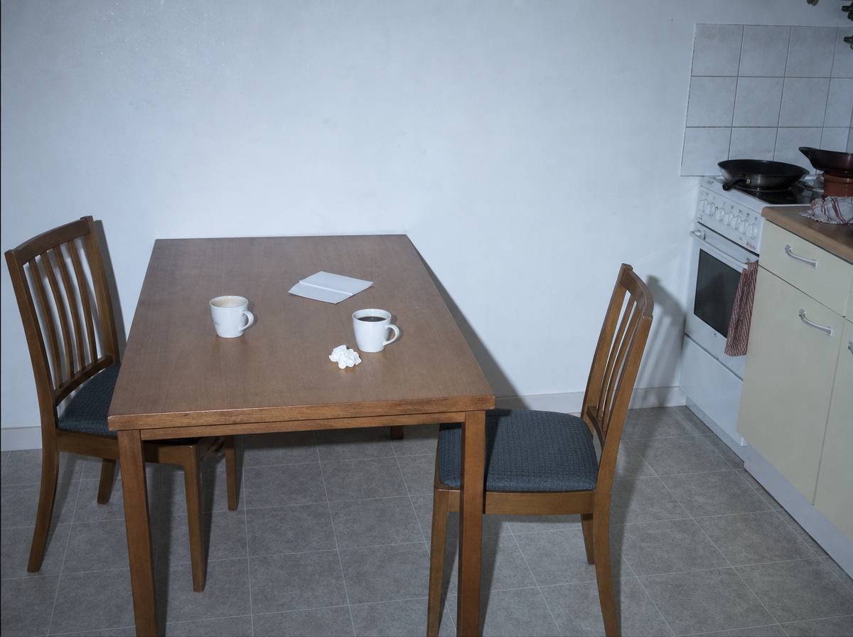 Kuchenny stół z dwoma kubkami i odsuniętym krzesłem po trudnej rozmowie o odmowie