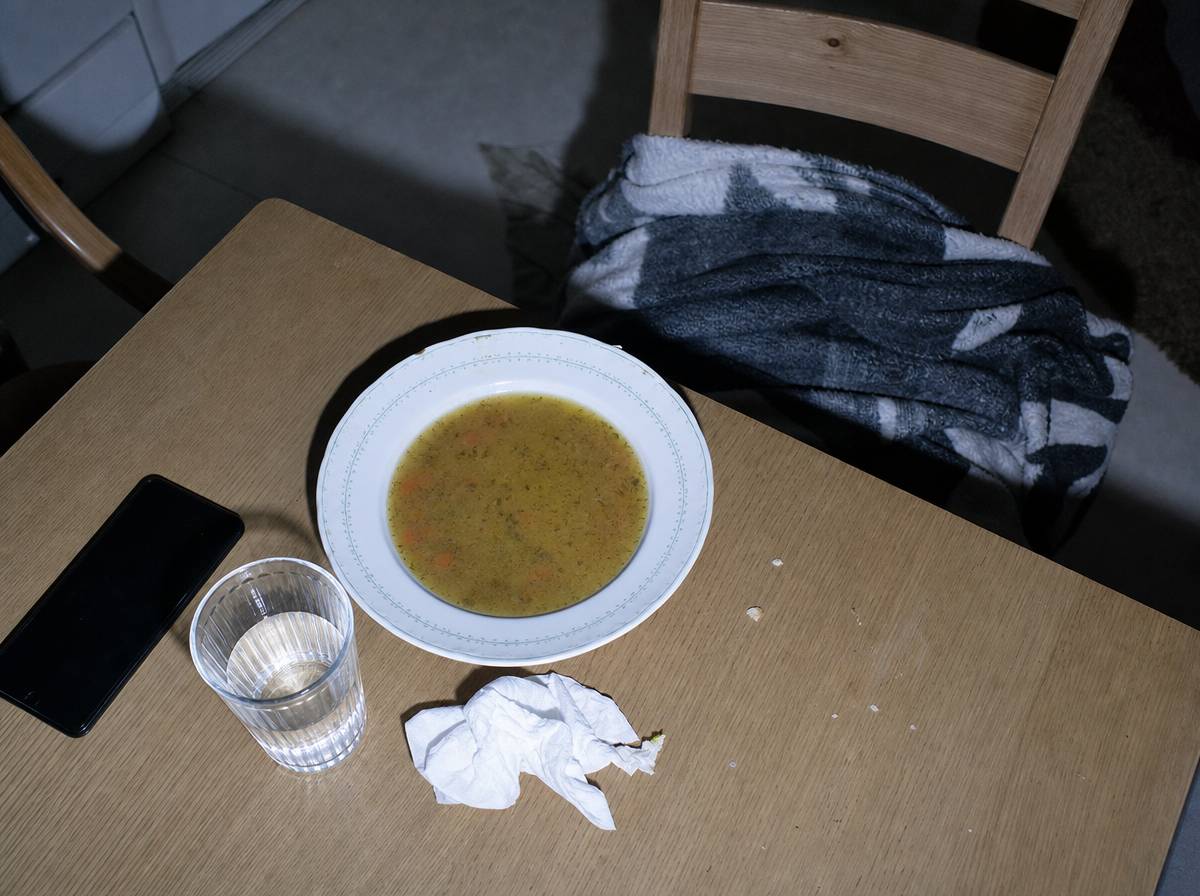 Nietknięty talerz zupy i odłożony telefon na kuchennym stole jako ślad objawów żałoby