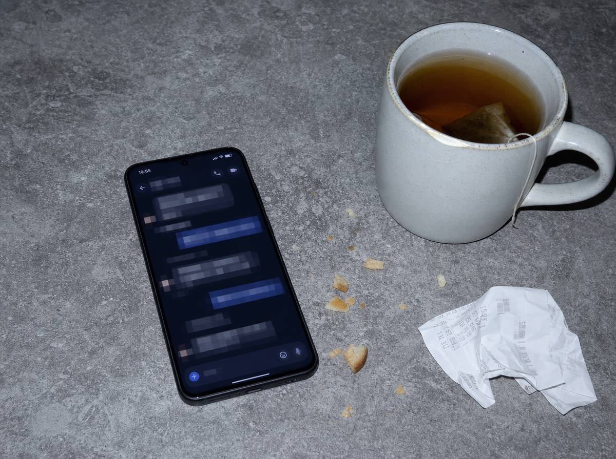 Telefon z otwartym oknem wiadomości na kuchennym blacie obok kubka herbaty