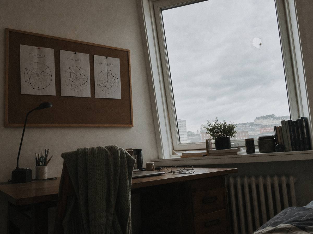 Trzy kartki z narysowanymi kołami życia przypięte do korkowej tablicy nad biurkiem pod oknem